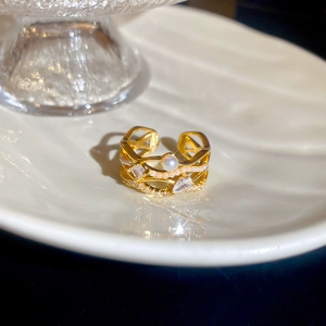 Macro shot of 18k gold ring with white pearl, teardrop zircon and layered hollow design
