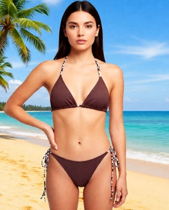 Detail view of deep brown bikini set with leopard print ties on a sunny tropical beach