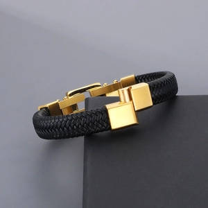 Macro detail of men's black woven leather bracelet with polished gold cube metal clasp