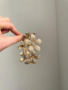 Close-up of golden floral metal bracelet featuring textured petals and crystal rhinestones
