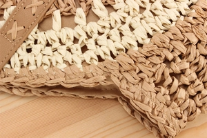 Detail of round beige and brown paper rope woven bag with hand-stitched leather strap