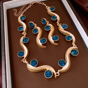Elegant gold necklace and earring set with blue rhinestones in a brown velvet box
