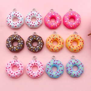 Macro shot of colorful resin donut pendants with sprinkles and metal hooks for DIY jewelry