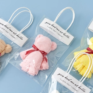 Close-up of bear-shaped coral fleece towels in multi-color gift packaging with ribbons