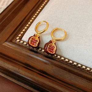 Nahaufnahme von Vintage Granatapfel-Ohrringen mit roter Emaille auf Holzdisplay