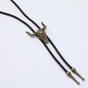 Detail view of a brass bull skull bolo tie with black braided leather and metal tips