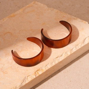 Retro amber tortoiseshell C-shaped resin hoop earrings on a textured stone surface