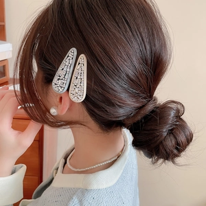Detail of light blue and beige rhinestone hair clips worn on a side hairstyle