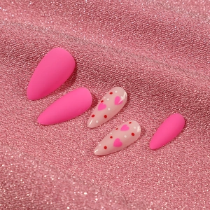 Matte rose pink and heart-patterned stiletto press-on nails on pink shimmering fabric
