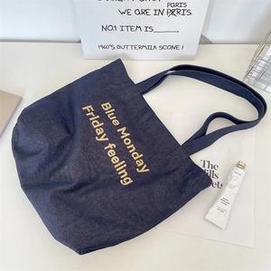 Dettaglio della borsa tote in denim blu con ricamo giallo e ampia tracolla in tela denim