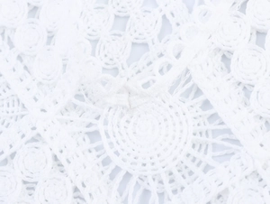 Detailed macro view of white crochet lace fabric with intricate hollowed-out patterns