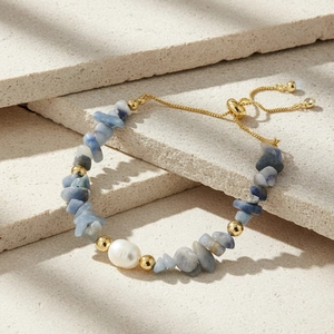 Detailed close-up of a blue gravel stone bracelet with a large natural white pearl and gold clasp