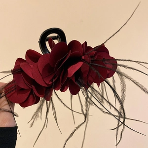 Detail of red layered fabric flower hair claw with black feathers and a sleek clip