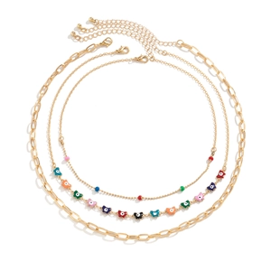 Detailed view of layered necklaces with colorful butterfly enamel and gold paperclip links