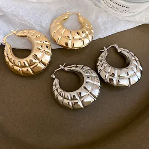 Polished gold and silver hoop earrings with a textured geometric quilted pattern