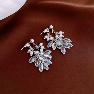 Close-up of silver tassel earrings with pearls and crystal leaf drops on dark velvet