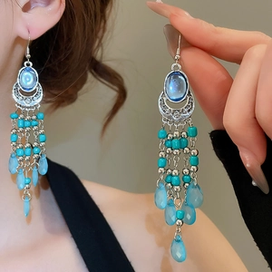 Detail of bohemian ethnic earrings featuring blue gemstones and long teardrop tassels