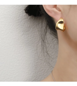 Close-up of model wearing gold irregular liquid metal earrings with a minimalist design