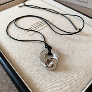 Detail of silver hollowed double heart pendant on black cord in elegant jewelry box