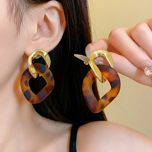 Vintage leopard print resin drop earrings with gold metal accents worn by a model
