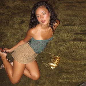 Detail of green floral tube top paired with khaki cargo skirt and gold handbag