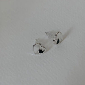 Detail of silver heart stud earrings with black enamel inlay and silicone backings