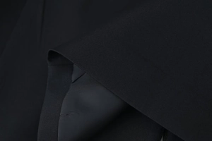 Detailed macro view of black woven fabric texture and inner lining on a women's blazer
