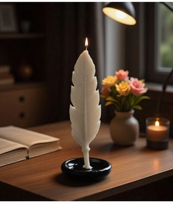 Detailed white feather-shaped aromatherapy candle lit on a black ceramic tray