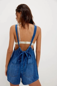 Detail of adjustable back tie and pocket structure on denim sleeveless overalls