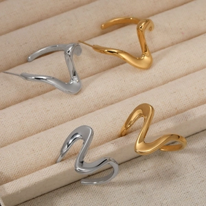 Modern gold and silver irregular wave earrings and rings set on a beige jewelry display tray
