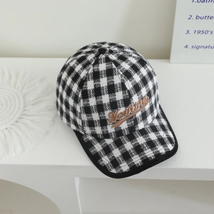 Checkered black and white baseball cap with brown Nothing embroidery on a display stand