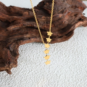 Elegant gold star tassel necklace displayed on rustic wood with a soft white backdrop