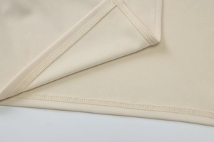 Gros plan des coutures et de l'ourlet en maille de qualité sur une robe d'été beige