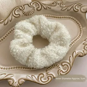 Close-up of white plush scrunchie with 5cm inner diameter on vintage ceramic tray