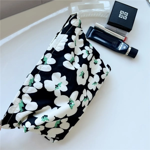 Floral print cotton makeup bag with green accents and zipper closure on white surface