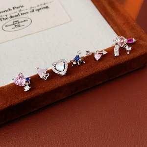 Detailed view of six assorted silver stud earrings with pink hearts and blue gems