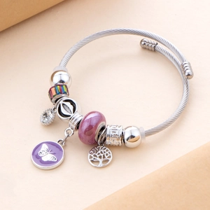 Detailed view of silver-plated charm bracelet featuring purple butterfly and tree charms