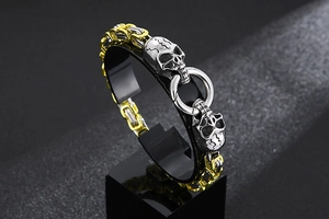 Detail of silver and gold skull head bracelet with a heavy link chain and ring connector
