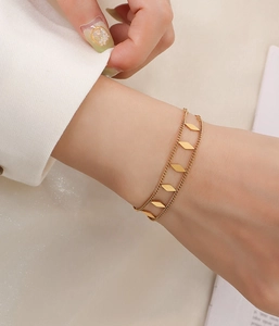 Close-up of double-layered gold bracelet with five geometric diamond-shaped charms