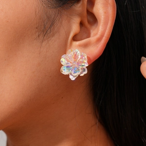 Close-up of a holographic resin flower stud earring worn on ear with iridescent finish