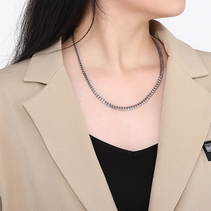 Close-up of a silver stainless steel Cuban link chain necklace worn by a fashion model