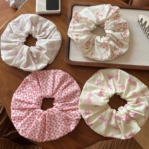 Close-up of four floral and bow print fabric scrunchies on a natural wooden table