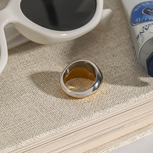 Detail shot of multi-layer gold and silver rings on a book next to white sunglasses