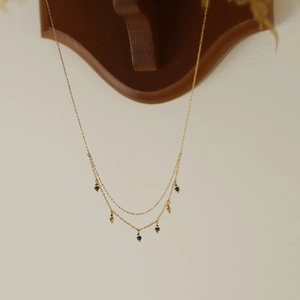 Detail of layered gold necklace with vintage blue beads and titanium steel gold plating