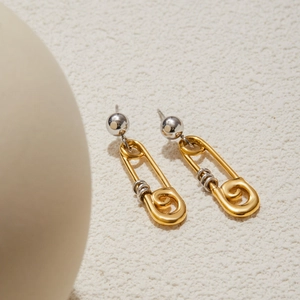 Détail de boucles d'oreilles épingle de sûreté en acier doré 18 carats et argenté sur pierre