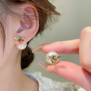Detail of honey bee earrings featuring faux pearl drops and shimmering inlaid crystals