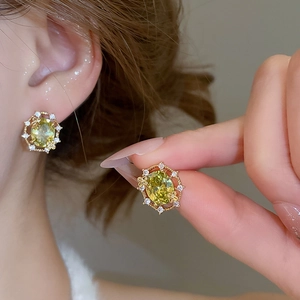 Detail of 18k gold plated earring with oval yellow gemstone and white zircon halo