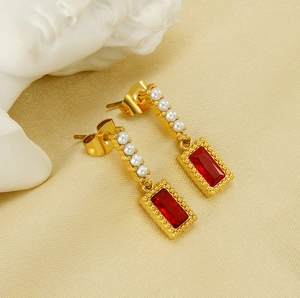 Macro view of vintage gold earrings with white pearls and a rectangular red crystal