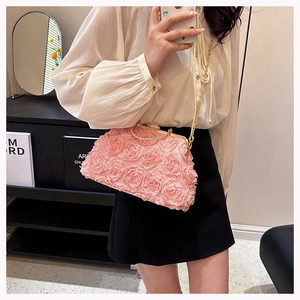Pink evening bag with 3D floral roses and a gold chain strap worn by a model