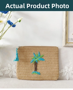 Detailed embroidery of palm trees on a beige woven clutch bag with a blue tassel charm
